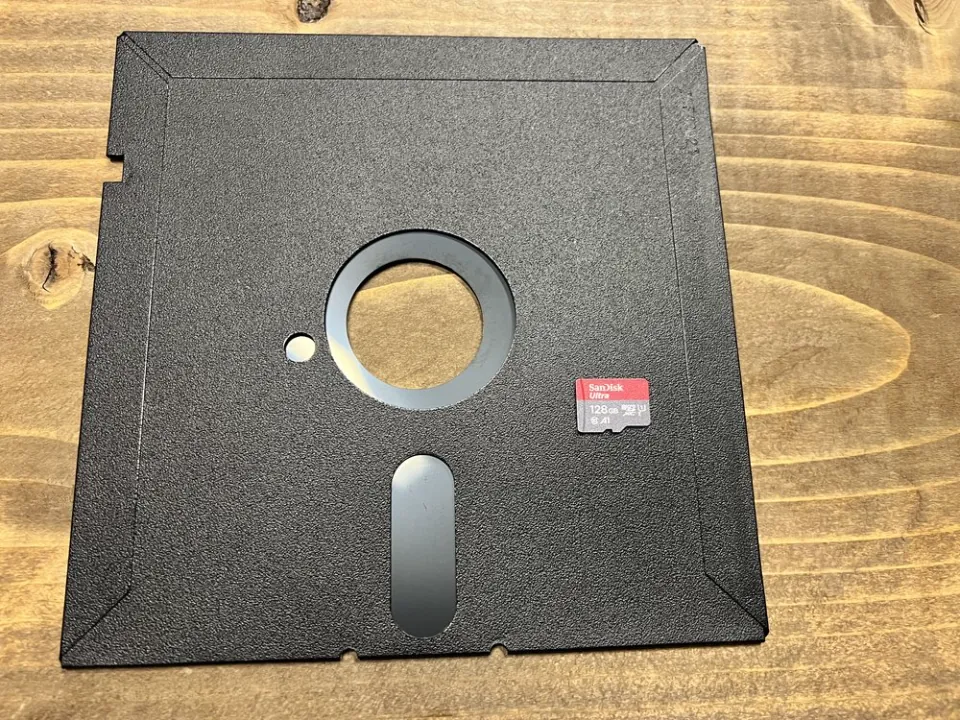 A 5.25-inch floppy disk with a modern 128GB microSD card resting on top of it