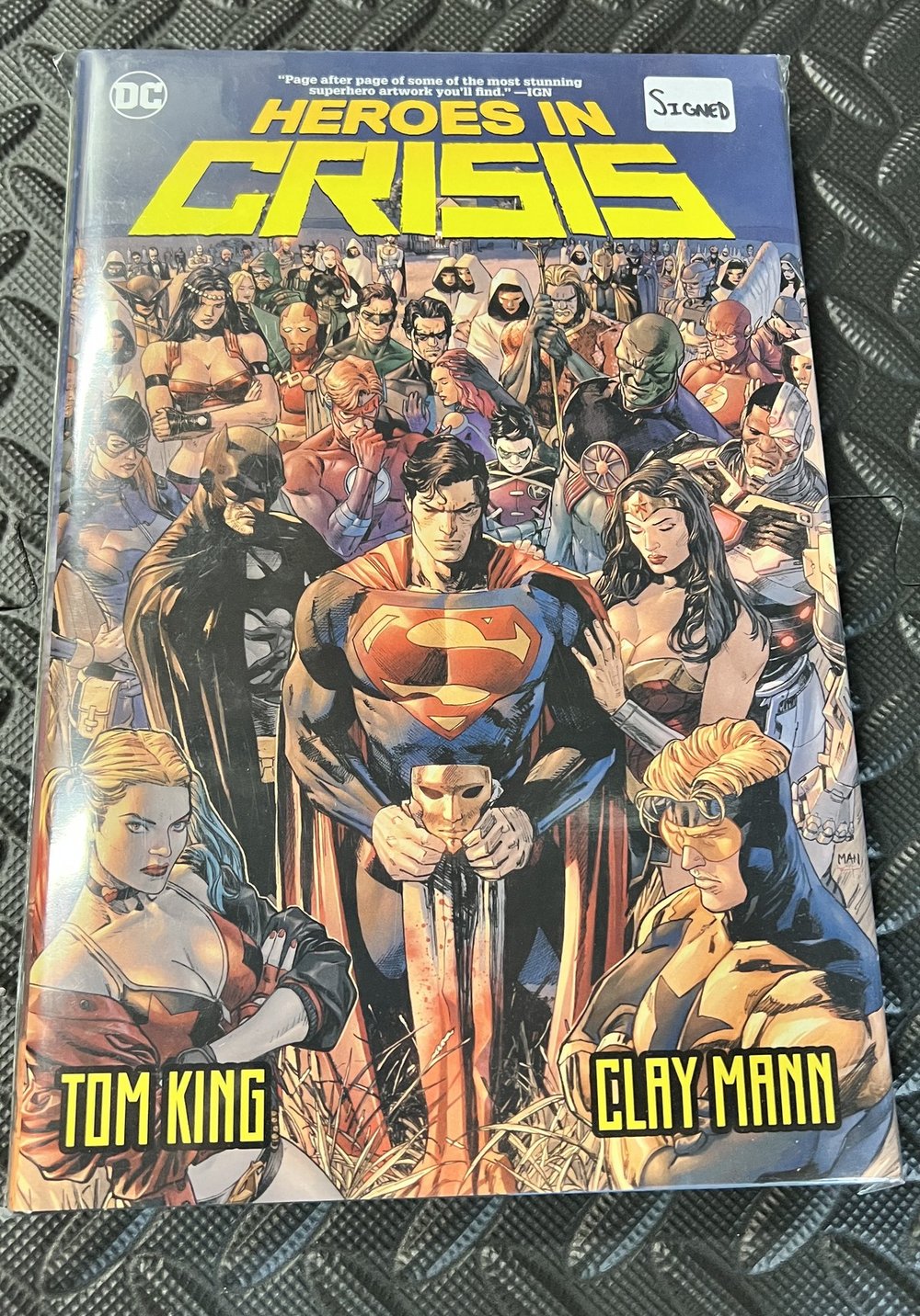 A bagged and boarded signed hardcover of Heroes in Crisis by Tom King and Clay Mann, the assembled heroes gathered in mourning on the cover, with a handwritten SIGNED label on the sleeve
